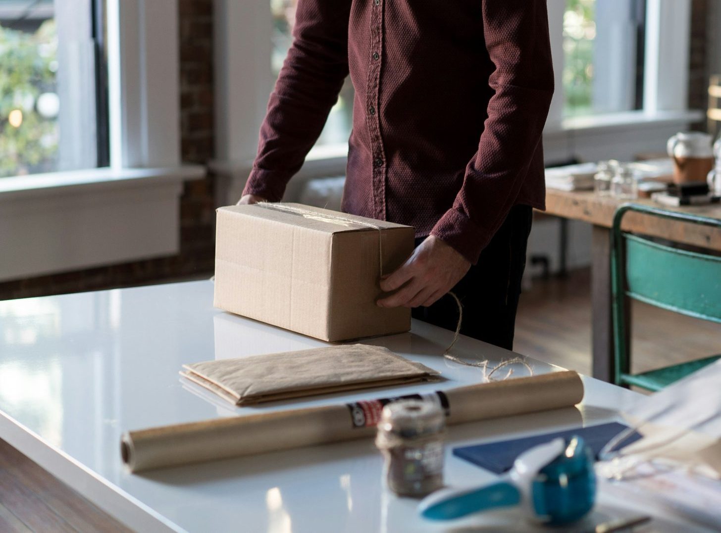 Persona sosteniendo una caja de cartón sobre una mesa